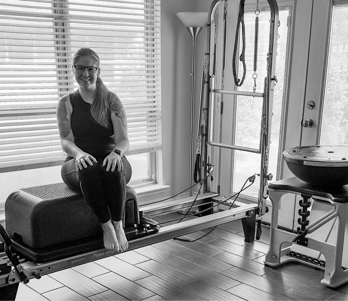Mary-Ann Zykin sitting on pilates reformer at home pilates studio.